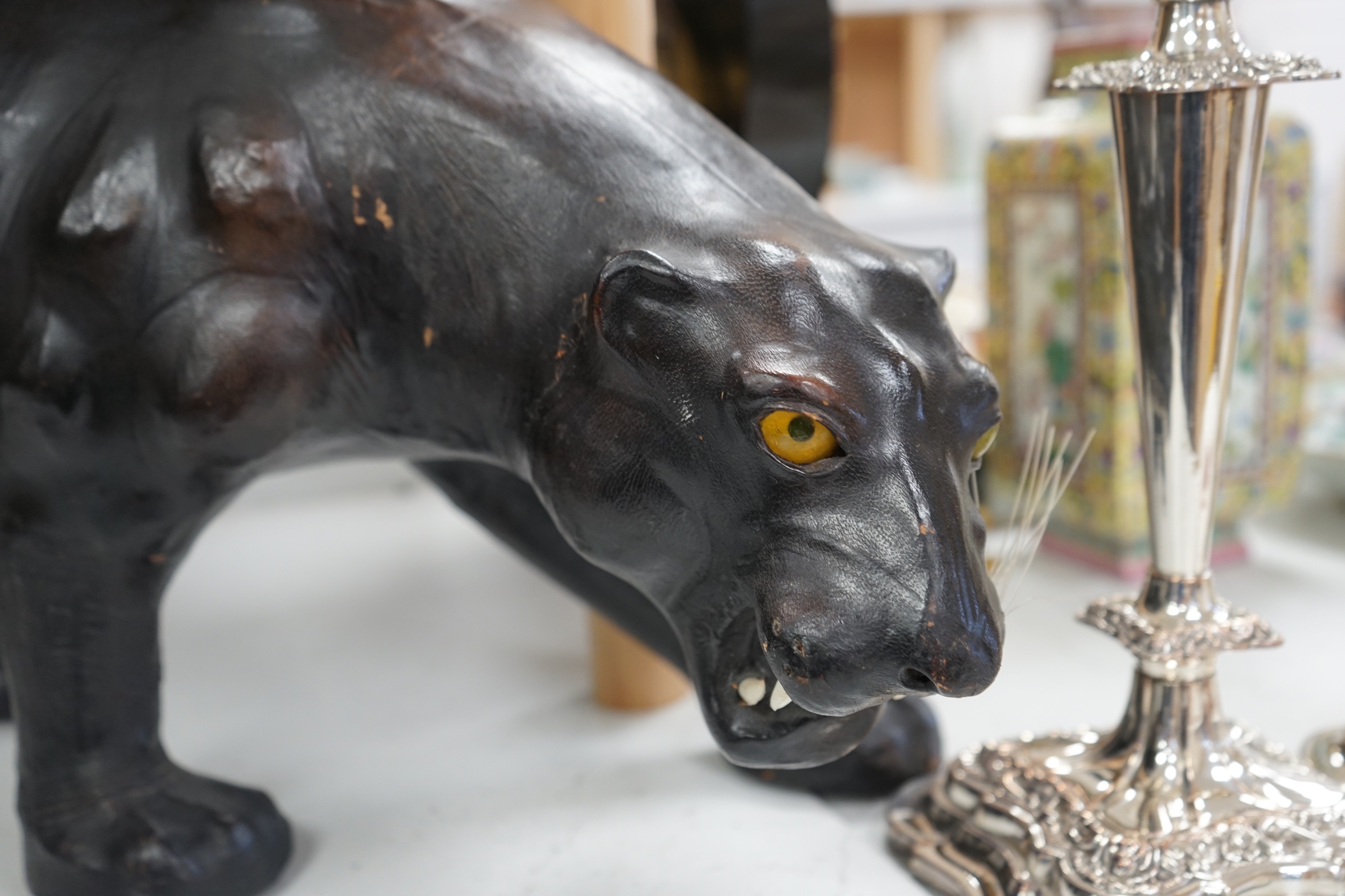 A Liberty’s-style black leather panther footstool, 75cm wide